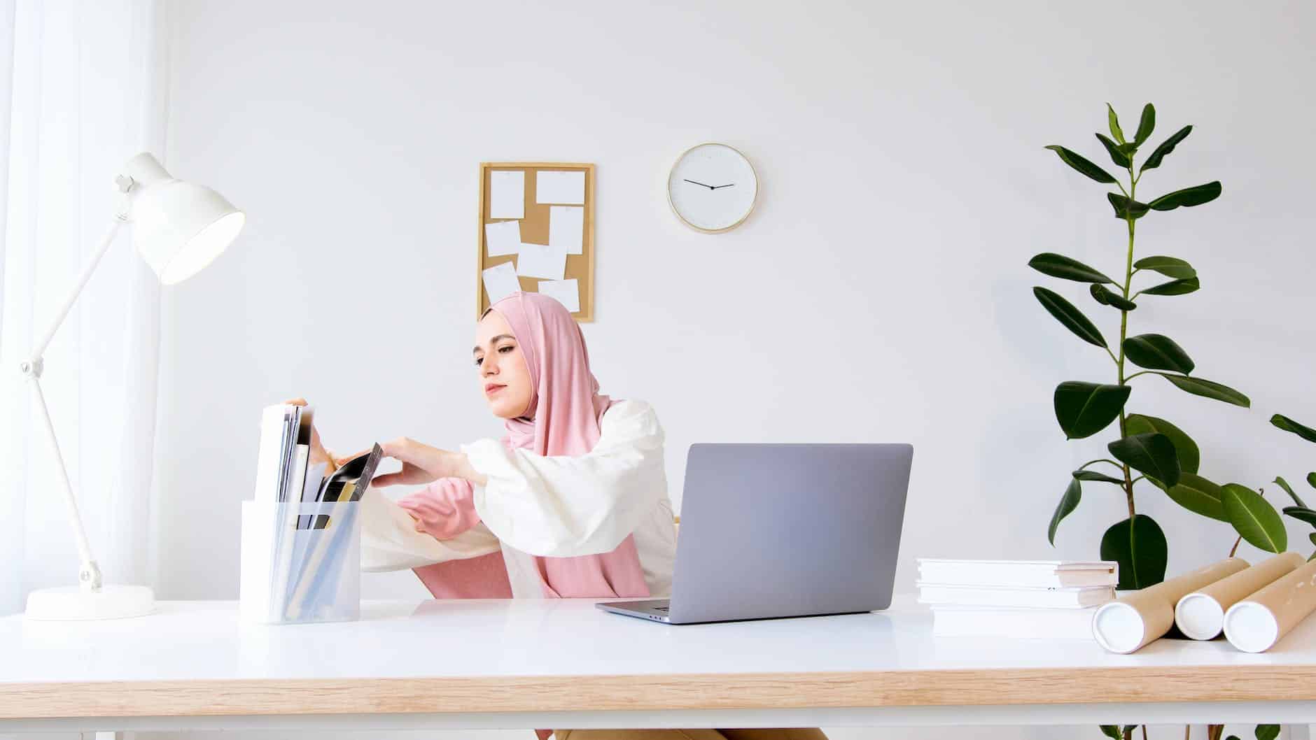 woman in pink hijab sitting on chair in front of a laptop